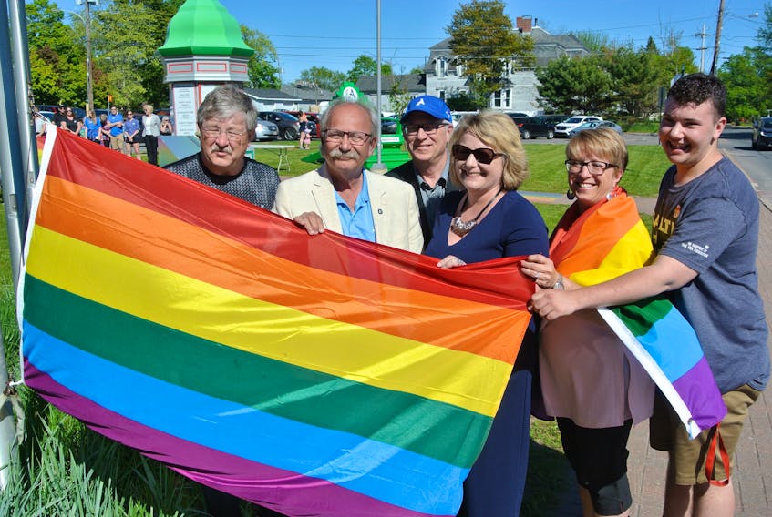 (From left) Amherst town councilor Vince Byrne, Mayor David Kogon, Bill Schurman of the northern zone community health boards, Deputy Mayor Sheila Christie, Michelle Richard from Cumberland Pride and Mark McLearn raise the Pride flag during a ceremony on Monday.