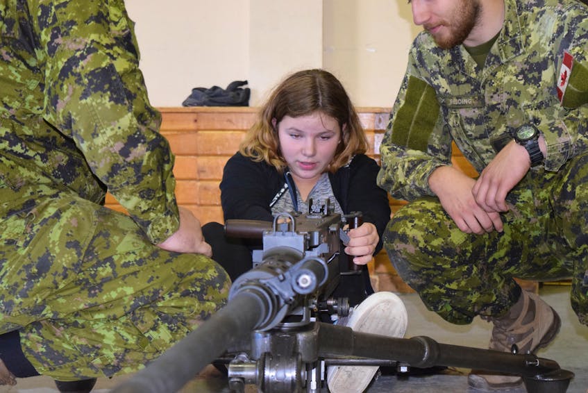Soldiers help Skylar Frizzell cock a 50-calibre machine gun inside the armoury during Saturday’s open house. It took a couple of attempts for her to get the hang of it. The army reserve group opened its armoury in Truro to the public on Sept. 29 to show the public what they do best - including target practice, radios and a marching band.