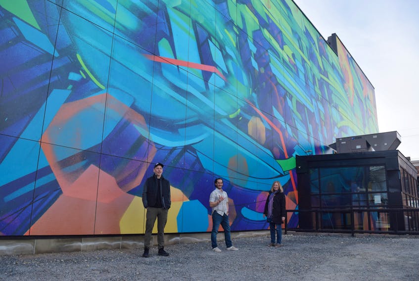 Developer Jamie MacGillivray, artist Christian Toth and New Glasgow Mayor Nancy Dicks stand in front of a mural Toth created for the side of the former Roseland Theatre building.