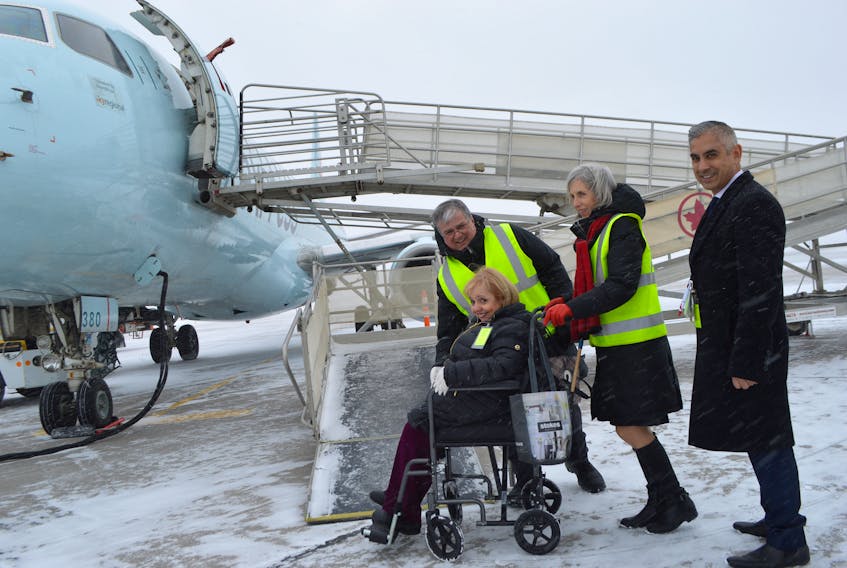 Marcie Shwery-Stanley, left, 71, of Sydney, is escorted by Air Canada officials from the left, Sydney agents Tony English and Clare MacDougall ,and Steve Sexton, manager of station operations for Air Canada, on Tuesday.