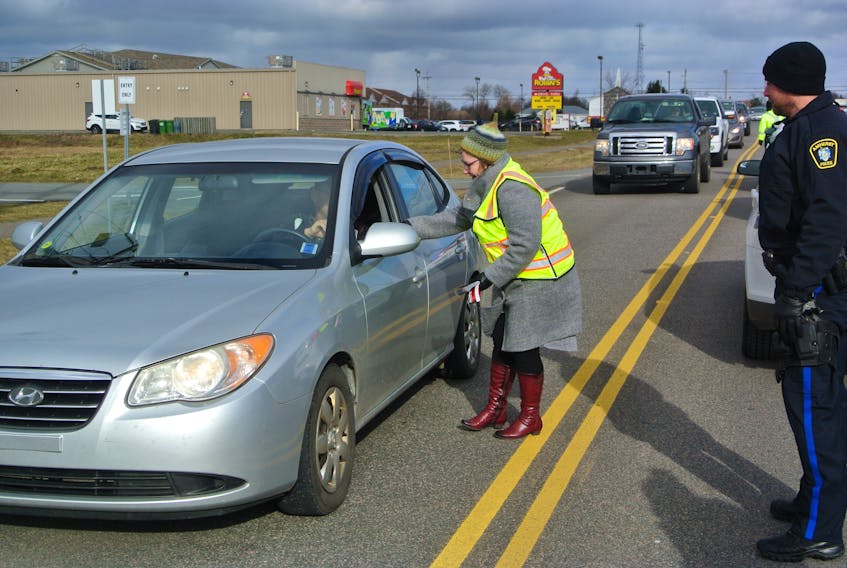 Amherst Deputy Mayor Sheila Christie gives a red ribbon to a motorist on Robert Angus Drive on Wednesday during the launch of MADD Canada’s Red Ribbon Campaign to raise awareness about impaired driving by alcohol or drugs.