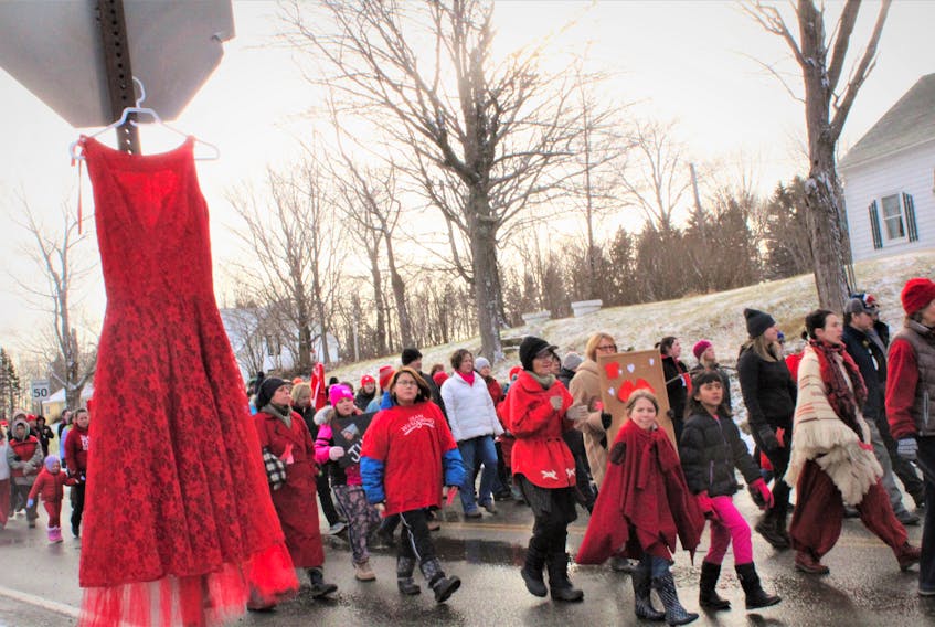 A red dress symbolizing missing and murdered Indigenous women was hung from a stop sign as a solemn group of about 70 people made their way toward Cassidy Bernard’s hometown of We’koma’q on Saturday.