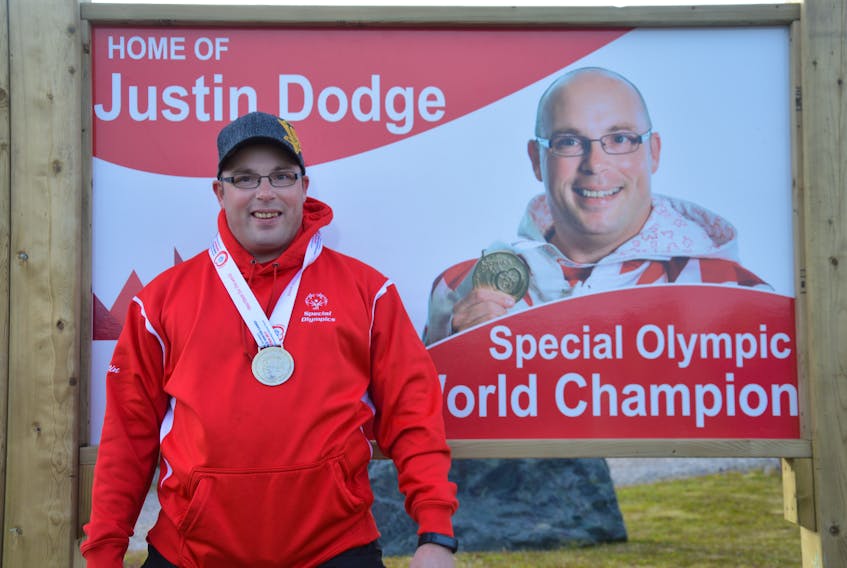 Justin Dodge pictured next to the sign placed at the entrance to Grand Bank on Route 220