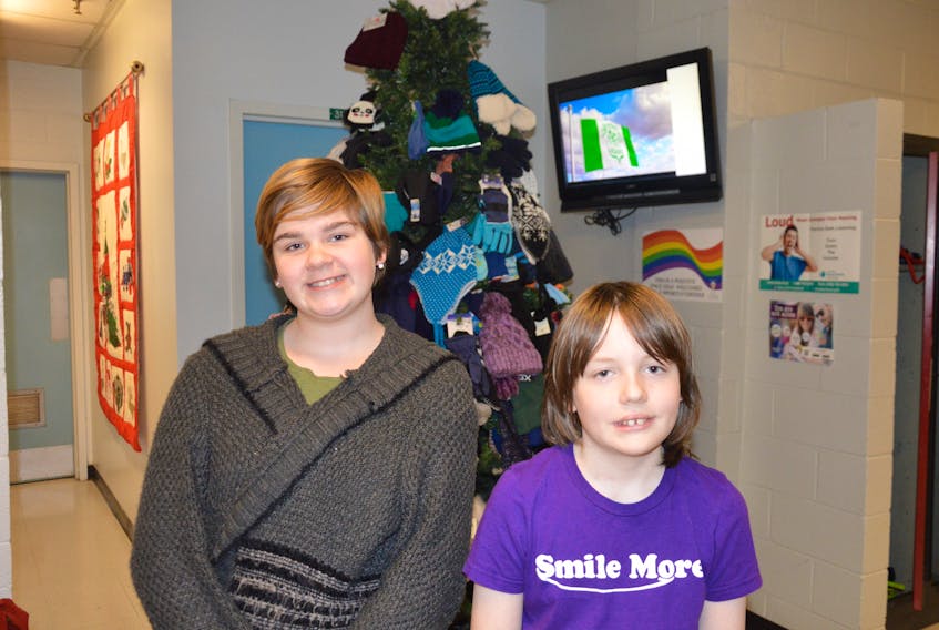 Emma Kilfoy and Ian Smith are both excited to be able to help provide winter hats and mittens to students in their school who may not have them. Donations to the hat and mitt drive are placed on a Christmas tree in the lobby of the school.