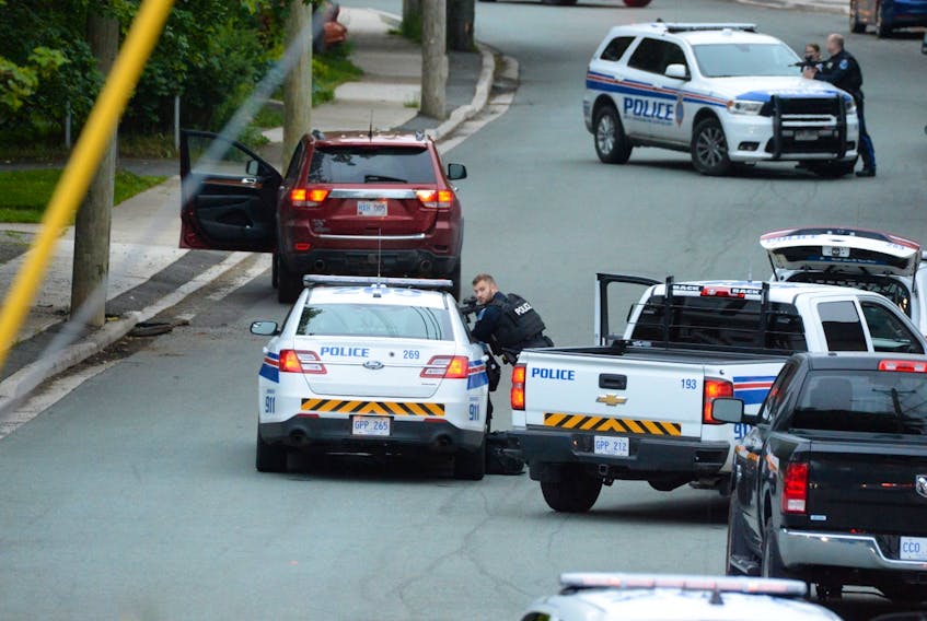 St. John's police shelter behind their vehicles at an apparent standoff scene on Craigmillar Ave. early Sunday morning. The RNC was called to the scene shortly after 4 a.m. and arrived to find the victim lying in the street, and a vehicle at the side of the road with the door open. Residents in the area were told to stay inside.