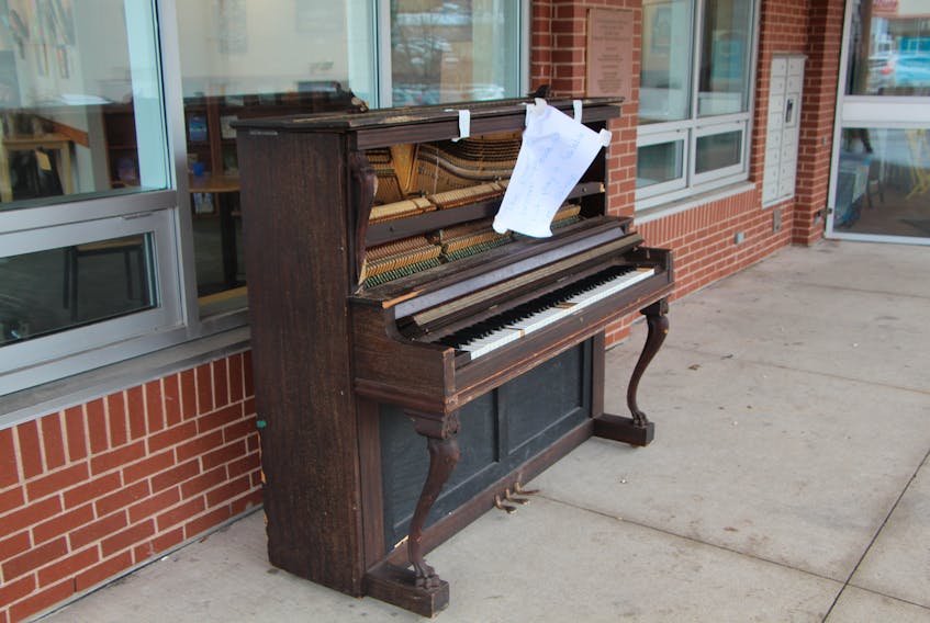 Heavily damaged after being tipped over by vandals, the community piano stands outside the People’s Place Library on Main Street. Staff at the library have encouraged people to salvage parts of the broken instrument.