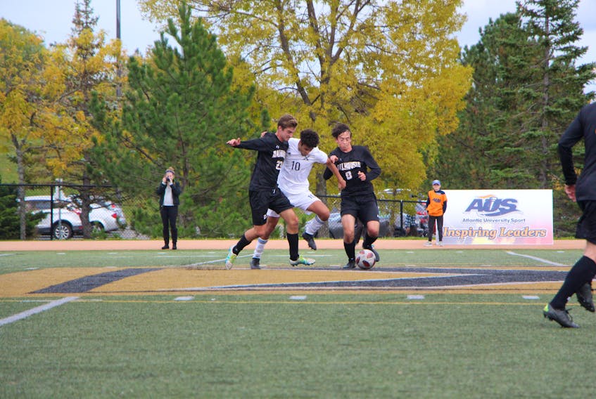 Midfield player Ayoub Al Arabi with the St. F.X. X-Men soccer team, pushing for the ball, flanked by opponents playing for Dalhousie.