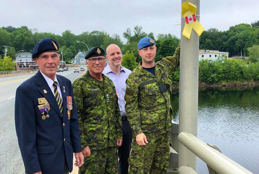 Bridgewater Legion president Wayne Thorburne, West Nova Scotia Regiment Honorary Col. Don Downe, Town of Bridgewater Mayor David Mitchell and Maj. Craig Bradshaw of the 14 Construction Engineering Squadron, attach the first of over 100 yellow ribbons in Bridgewater on Tuesday, July 17.