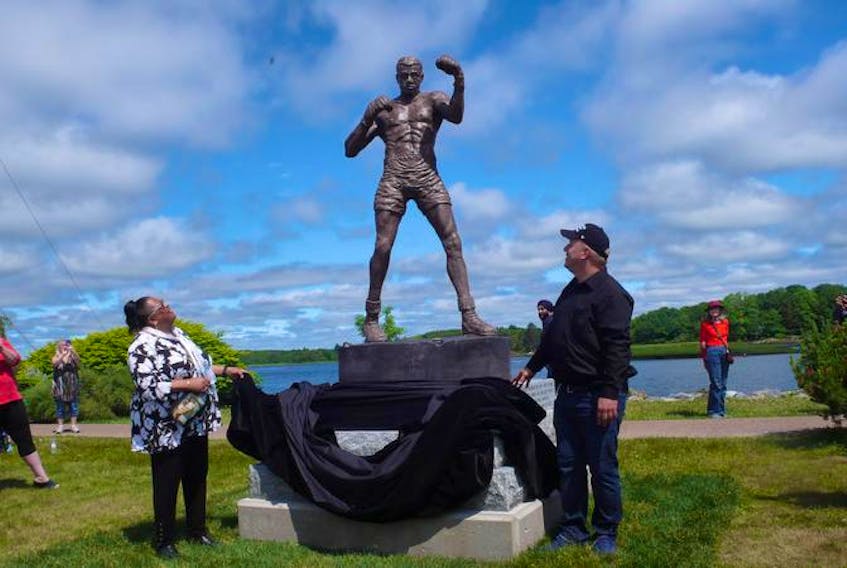 Sharon Johnson, daughter of Terrance “Tiger” Warrington, and local historian Tim McDonald who envisioned the project more than 20 years ago, unveil the statue of Tiger Warrington that is located on Liverpool’s waterfront in Privateer Park.