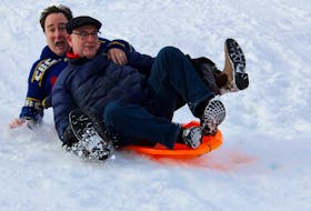 Victoria Park Foundation chair Mark Critch (left) and City of St. John's Mayor Danny Breen slide down a hill during the community sledding event at the historic downtown park.