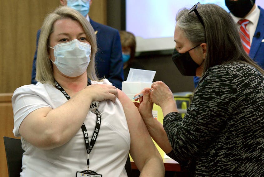 Ellen Foley-Vick (left), a registered nurse with public health, is given the first COVID-19 vaccination in the province by Chief Medical Officer of Health Dr. Janice Fitzgerald Wednesday afternoon. Keith Gosse/The Telegram