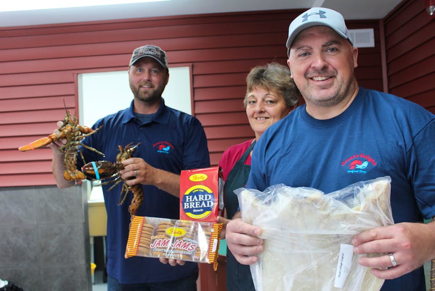 Ocean’s Delight Seafood Shop co-owner Greg Collett (left) holds fresh lobster in stock at the newly-opened store in Paradise. Also pictured is manager Cora Brown (middle) and co-owner Blair King (right). -Juanita Mercer/The Telegram