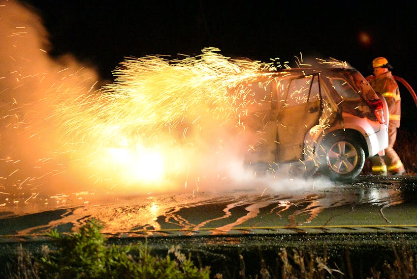 Firefighters extinguish a vehicle fire on the T.C.H. Tuesday night. Keith Gosse/The Telegram