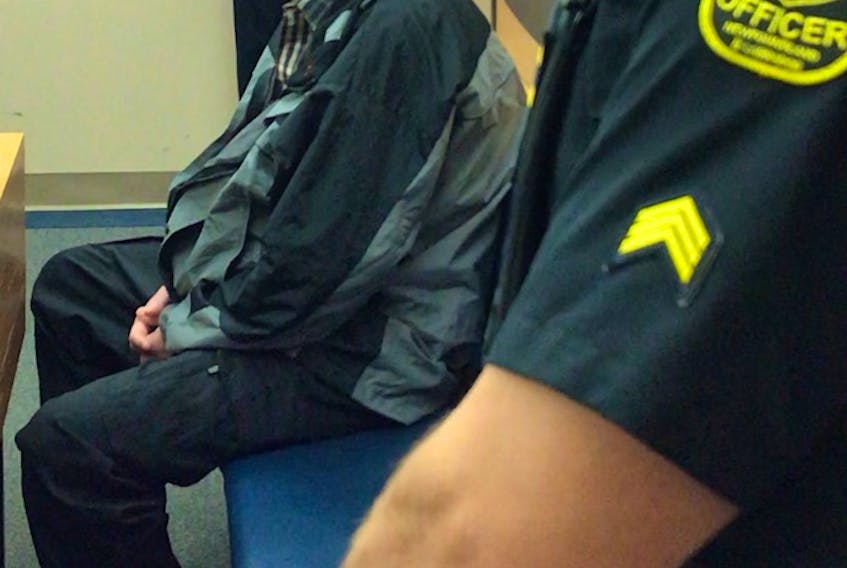 Jamie Kennedy, 41, sits flanked by sheriffs in a provincial courtroom in St. John’s Monday as he waits for his co-accused, Cory Quilty, to enter and their trial to begin. The two men are charged in connection with an attempted robbery of a bank with a stolen front-end loader last January.