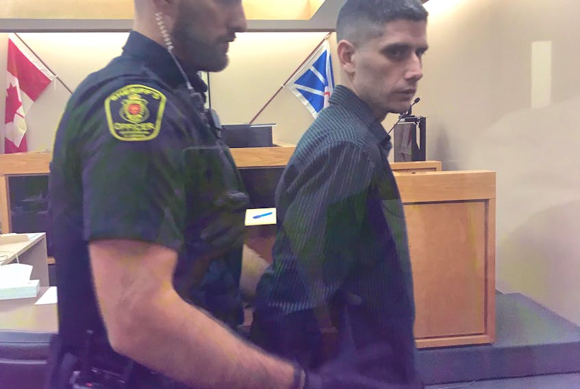 A sheriff prepares to escort Andrew Parsons from a St. John’s courtroom Tuesday after he received the first of two prison sentences for armed robberies.