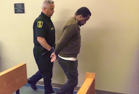 Joseph Kalombo Ndonki, 46, leaves the courtroom with sheriffs following his sentencing hearing in St. John's Wednesday morning. He is set to be sentenced next month for identity theft crimes.