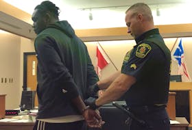 A sheriff removes handcuffs from Doudou Kikewa Mpumudjie’s wrists as his court case gets underway in St. John’s Friday. The Montreal man is one of four men charged together with identity theft and fraud.