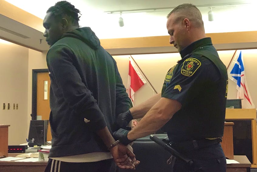 A sheriff removes handcuffs from Doudou Kikewa Mpumudjie’s wrists as his court case gets underway in St. John’s Friday. The Montreal man is one of four men charged together with identity theft and fraud.