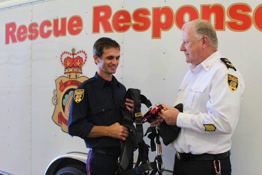 St. John's Regional Fire Department firefighter Chris George, a member of the high-angle rescue team, examines harness equipment with Deputy Fire Chief Richard Mackey.