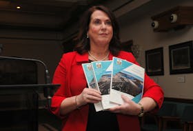 Natural Resources Minister Siobhan Coady holds portions of the six-volume final report from the Commission of Inquiry Respecting the Muskrat Falls Project, titled "Muskrat Falls: A Misguided Project."