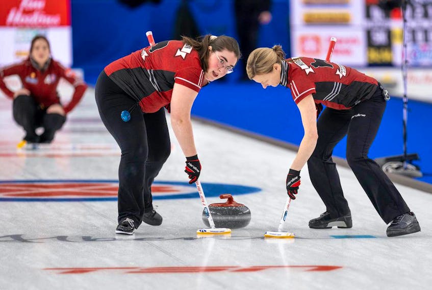 Newfoundland and Labrador's Lauren Barron (left) and Adrienne Mercer sweep a shot by skip Sarah Hill (background) during the Scotties Tournament of Hearts in Calgary. The N.L. team takes a 2-4 record into its final two round-robin games Thursday. — Andrew Klaver/Curling Canada