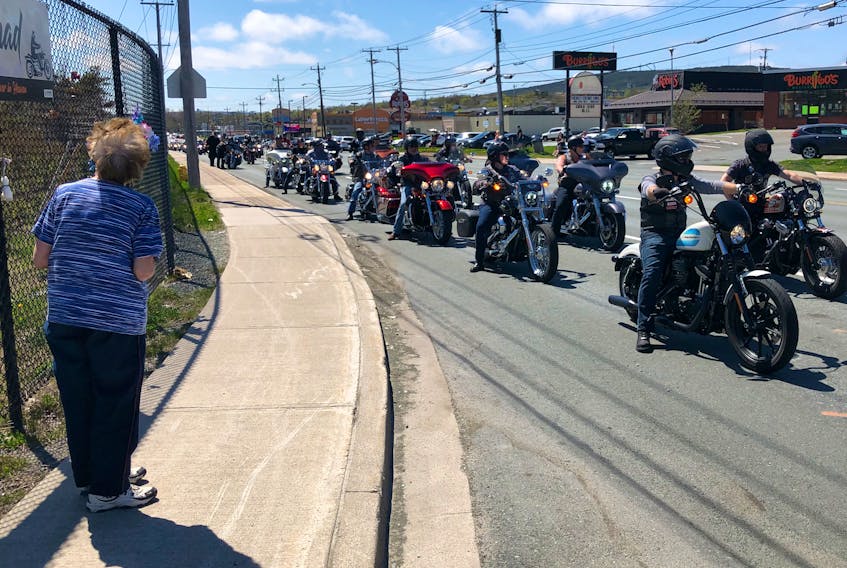 Motorcyclists taking part in the Chad Pitcher Memorial Drive stream past the spot on Topsail Road where Pitcher lost his life on May 11. Looking on at left is Dorcas Elms.