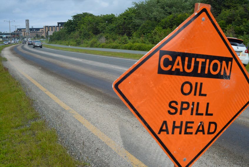 Warning signs and absorbent material are seen along the trail of spilled cooking oil on the Prince Phillip Parkway in St. John's Tuesday afternoon.