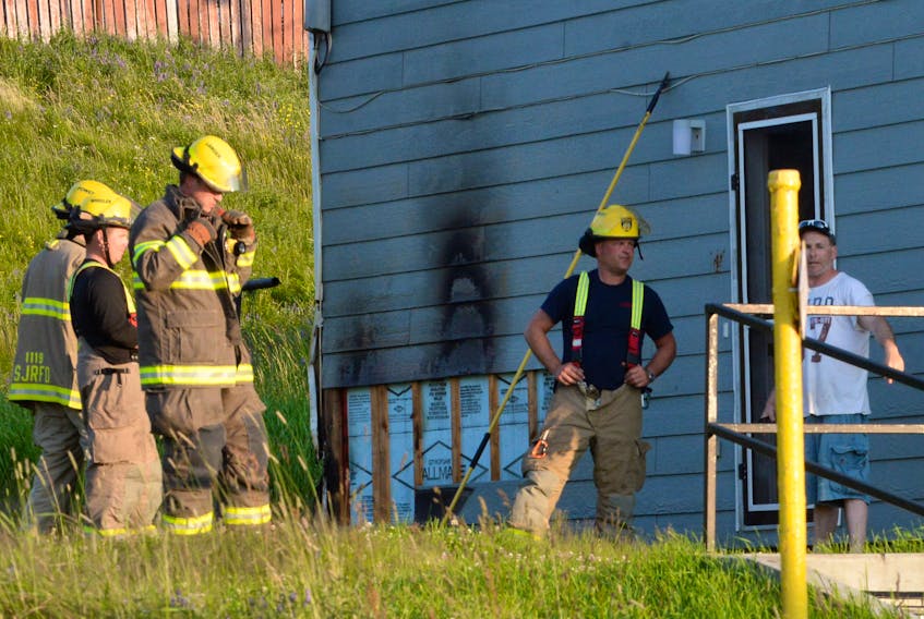 Firefighters chat with a man after responding to a fire call at the house Thursday evening. The man’s son put the fire out using a garden hose, but siding on the house sustained minor damage.