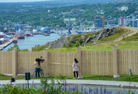 CBC "Here & Now" reporter Meg Roberts and cameraman Gary Locke prepare a news story for the Wednesday evening supper-hour newscast on the controversial new fence next to the Signal Hill Visitor Information Centre on Wednesday afternoon. Parks Canada said Wednesday it will remove the fence.