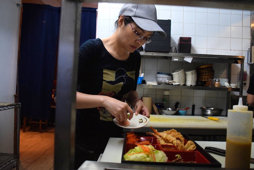 Cook Mia Pham carefully arranges sashimi, salad, tempura and a teriyaki dish in a lunchtime bento box for one of her customers at Sushi Way in Truro on Aug. 9. The restaurant is open again for business after a three-year break.