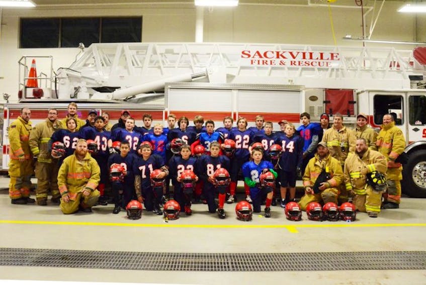 Sackville’s PeeWee Titans football team poses for a photo with members of the Sackville Fire & Rescue Department following an evening practice last week. Thanks to the fire department, the minor football program was able to acquire 24 new helmets this season.  KATIE TOWER-SACKVILLE TRIBUNE-POST
