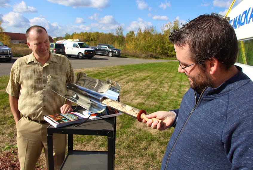Peter Bennett, left, president of Stright-MacKay Ltd., and Eric Maldre of Stright-MacKay check chicken cooking in the GoSun Sport solar oven.   Stright-MacKay is the only marine dealer in the area distributing the new solar cookers that can prepare meals solely through the heat of the sun.