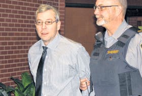Leslie Greenwood is led into Supreme Court in Kentville Wednesday for his trial on two charges of first-degree murder in the deaths of Barry Mersereau and Nancy Christensen in September 2000.