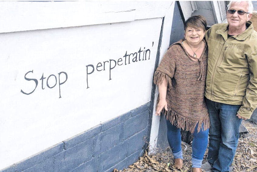 Jane Rozee and her partner Wayne Outhouse pose for a photo next to the Stop perpetratin’ sign on their shed near the Armdale Roundabout on Wednesday afternoon. RYAN TAPLIN • THE CHRONICLE HERALD