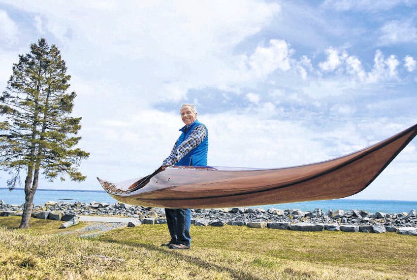 Vernon Shaffner hoists one of his hand-built wooden kayaks in front of his cottage near Green Bay on Wednesday. More than 600 hours of labour goes into making one of his sea kayaks. TIM KROCHAK • THE CHRONICLE HERALD