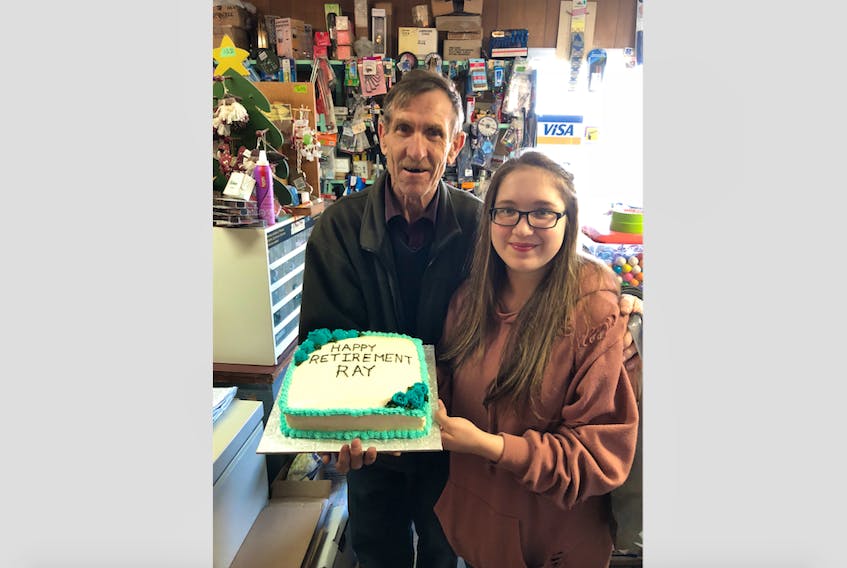 Lisa Hart’s daughter, Chloe, 14, and retiring store owner Ray Ginn, with the cake the Hart family made to celebrate Ginn’s retirement.