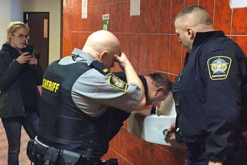 Deputy sheriffs help Darrin Rouse flush his eyes after he was sprayed with a sensory irritant during a scuffle with deputies at Kentville Supreme Court earlier this year.