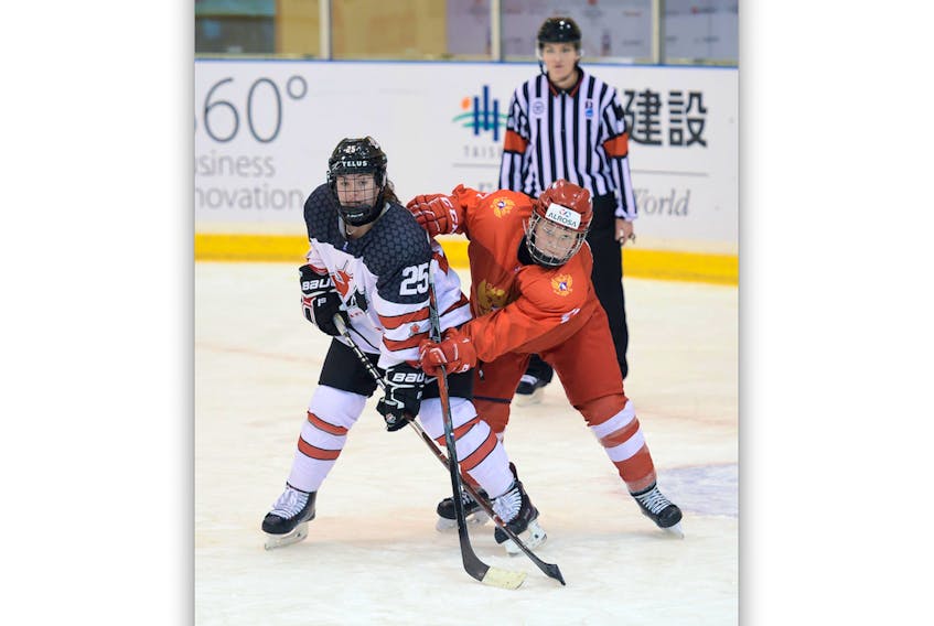 Canada’s Shailyyn Snow (25) battles with a Russian player in Russia’s defensive zone during their preliminary-round game at the world under-18 women’s hockey championship in Obihiro, Japan. Snow, who is from Clarke’s Beach, and her Canadian teammates are headed to the semifinal round of the tourney after a 5-1 win over the Russians. — Steve Kingsman/HHOF-IIHF Images