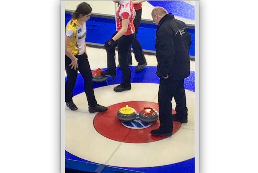 An official eyeballs two rocks, one for Manitoba (at left) and the other for Newfoundland and Labrador, both owning a piece of the button at the conclusion of their preliminary-round game at the Canadian junior women’s curling championship in Prince Albert, Sask., Sunday night. A measurement would show the Manitobans were closest to the pin, giving them an 8-7 win.