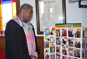 Pastor Brian O. Johnston looks at a photo display of an African Heritage Month celebration at his church.
