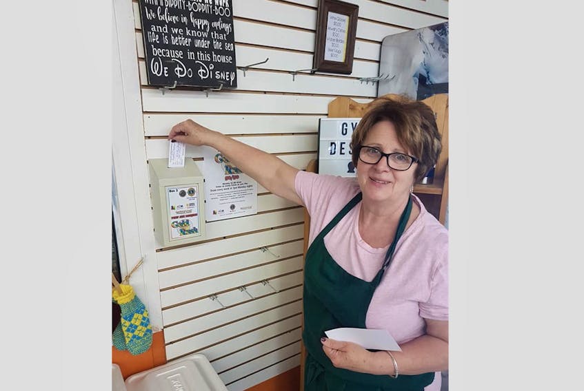 Jackie Musseau places a registration ticket and her toonie in the Gold Rush box at First Choice Convenience Store.