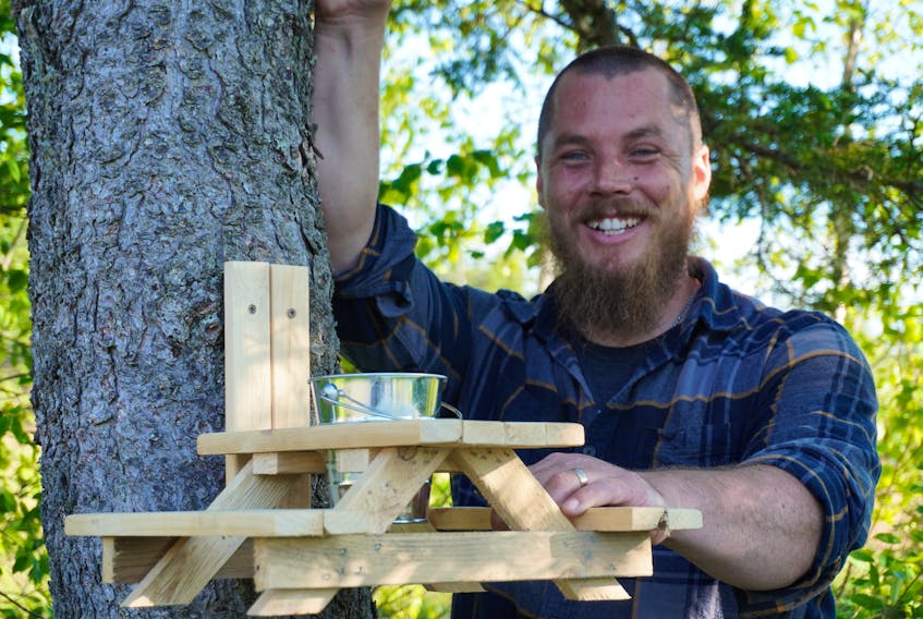 Shawn Spence showcases one of his miniature picnic tables which he designed for squirrels.