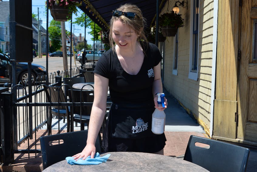Erin Hannah, a server at Hunter's Ale House on Kent Street in Charlottetown, wipes off a table on Tuesday. Hunter's isn't planning to have live music this summer, but the Beer Garden across the street is bringing back live music on Friday evening.