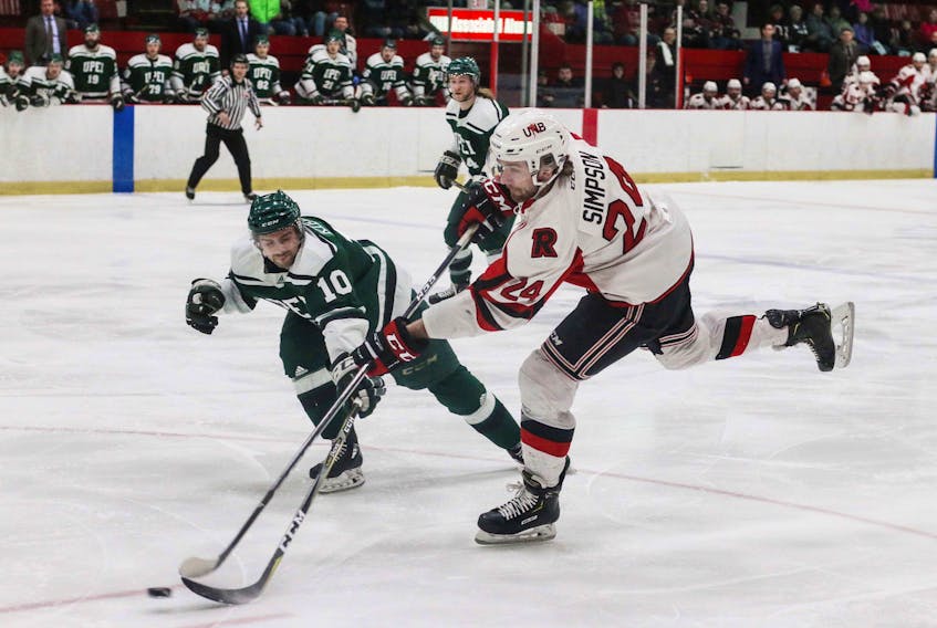 UNB Varsity Reds forward Mark Simpson fires a shot towards the UPEI goal while being defended by Kameron Kielly Friday in Fredericton, N.B., during Game 2 of the Atlantic University Sport semifinal. James West Photography