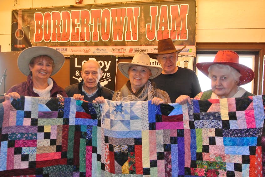 Singing for the Fling organizers (from left) Vicki Daley, LeRoy Morris, Ida Roode, Roy Pettigrew and Ruth Guilderson hold up a hand-stitched quilt that will be among the items auctioned off during Singing for the Fling on Wednesday, May 9 at Heartz Hall in Trinity-St. Stephen’s United Church.