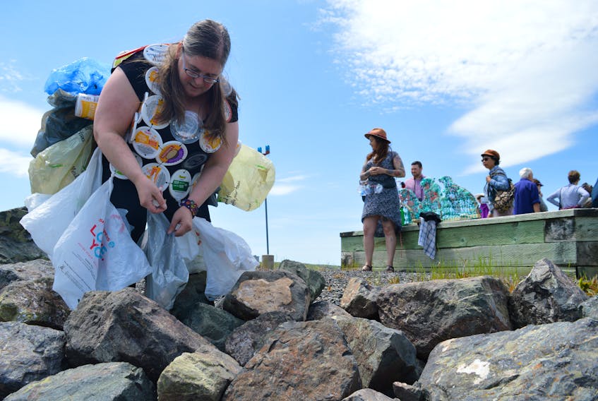 Sheila Christie, left, is shown picking up various pieces of plastic trash in front of the Merchant Mariner monument at Sydney harbour. Christie was on hand as part of Cape Breton Extinction Rebellion group that was raising awareness about illegal dumping in oceans, and environmental and health effects of single use plastics. The activists were dressed in clean plastic garbage as they distributed flyers along the waterfront and picked up trash. On the right, is Suzie Orm-Aylward who created a wave from plastics and garbage found on beaches. Note shown is Scott Sharplin, the coordinator of the event.