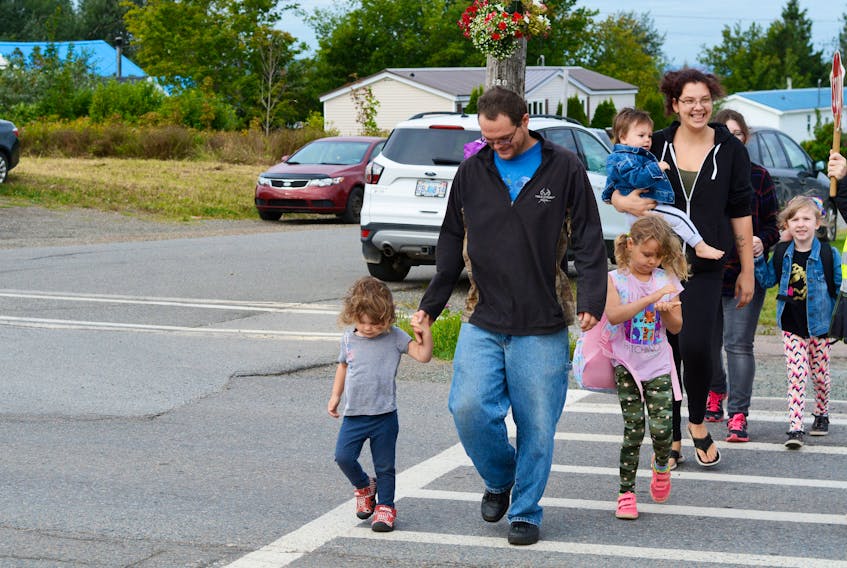 Kids and parents cross the crosswalk.