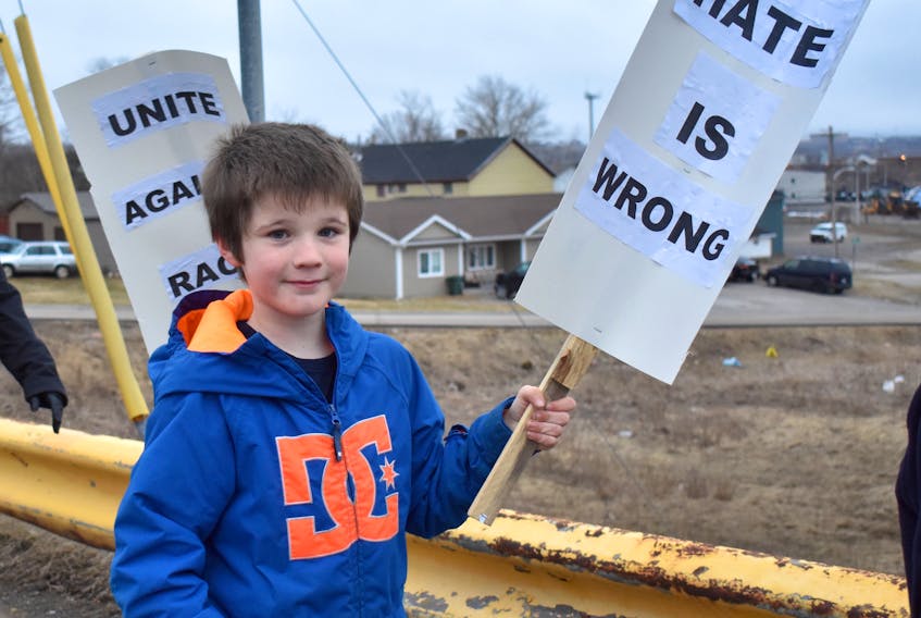 Dominick MacPherson of Bras d’Or holds a sign reading “Hate is wrong,” as he walks across the Whitney Pier overpass Friday evening. Members of the Cape Breton community came together for a Walk against Racism. About 20 people attended the 20-minute walk.
