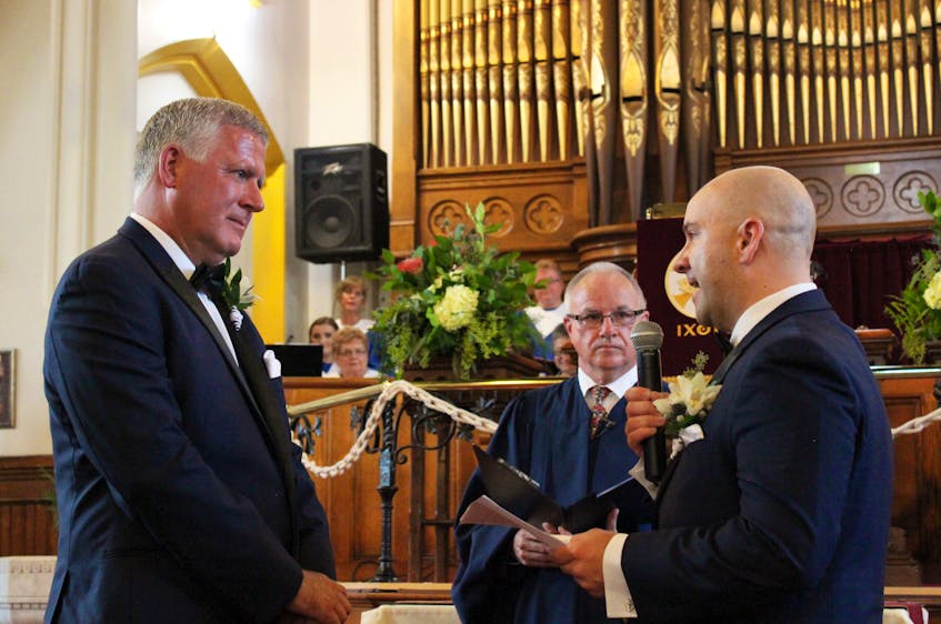 CBRM Mayor Cecil Clarke, left, and his partner Kyle Peterson, of Sydney Mines, reciting vows they wrote themselves, while a happy and emotional Rev. Stephen Mills reacts, during their wedding at the St. Matthew Wesley United Church in North Sydney on Saturday. Photo by Leah Batstone