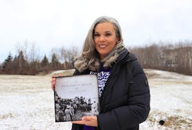 Amanda Carvery-Taylor holds up her new book called A Love Letter to Africville at a field near her home in Halifax on Sunday, Feb. 7, 2021. The book is a compilation of personal stories and photos from former residents of Africville, including Carvery-Taylor's own father, Frank Carvery.
